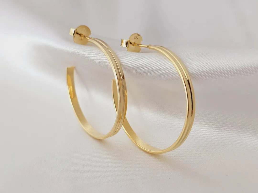 Argola retangular com friso no centro banhada a ouro
