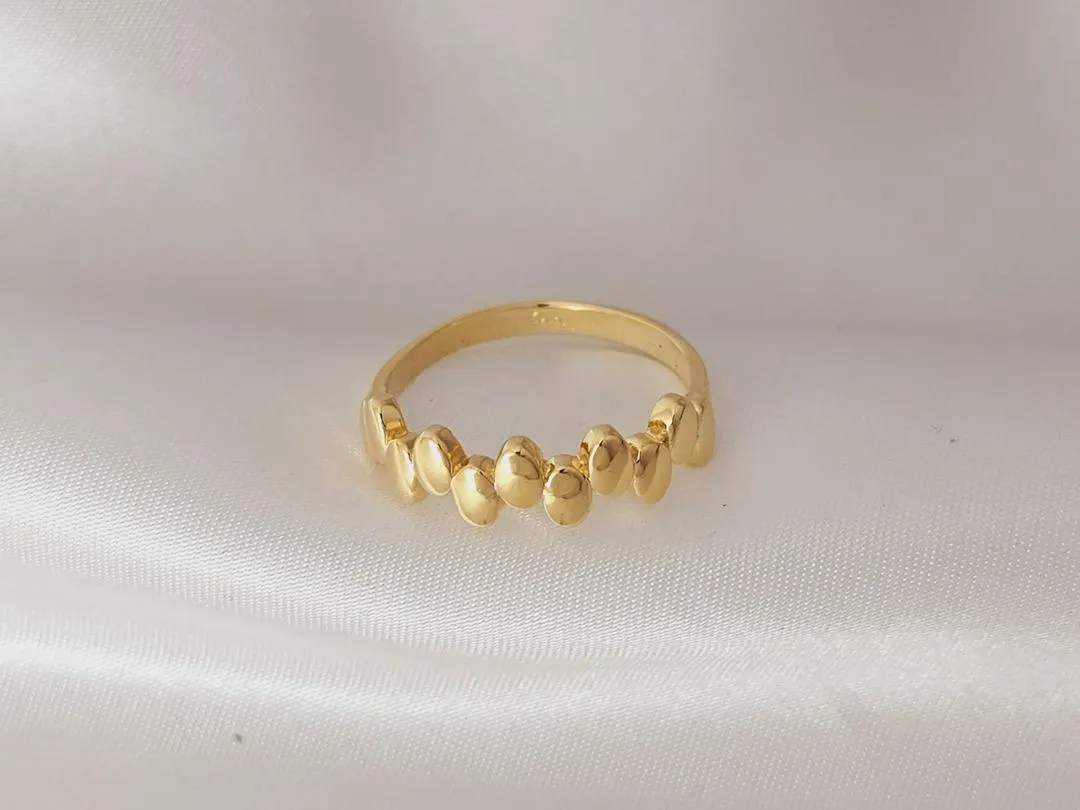 Anel com bolas ovais pequenas intercaladas, banhado a ouro, medindo 0,6cm de espessura