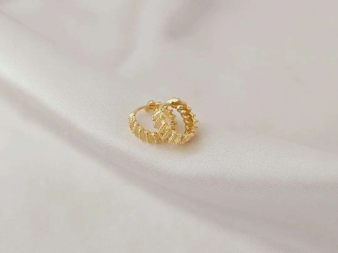 Argola com linhas inclinadas trabalhadas banhadas a ouro, medindo 1,2x0,5cm
