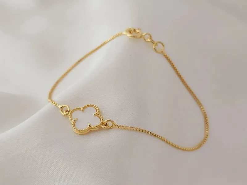 Pulseira com trevo marmorizado branco no meio, banhado a ouro, medindo 28cm.