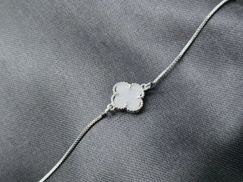 Pulseira com trevo marmorizado branco no meio, banhado a prata, medindo 28cm.
